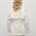 Back view of white elodianna jacket on model wearing white shirt and white trousers, against a white background.