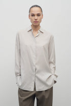 Front view of Long sleeve silk shirt in white with grey on brunette haired model  worn with khaki trousers.