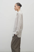 Side view of Long sleeve silk shirt in white with grey on brunette haired model  worn with khaki trousers.