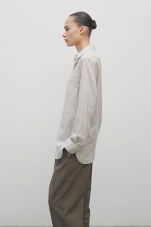 Side view of Long sleeve silk shirt in white with grey on brunette haired model  worn with khaki trousers.