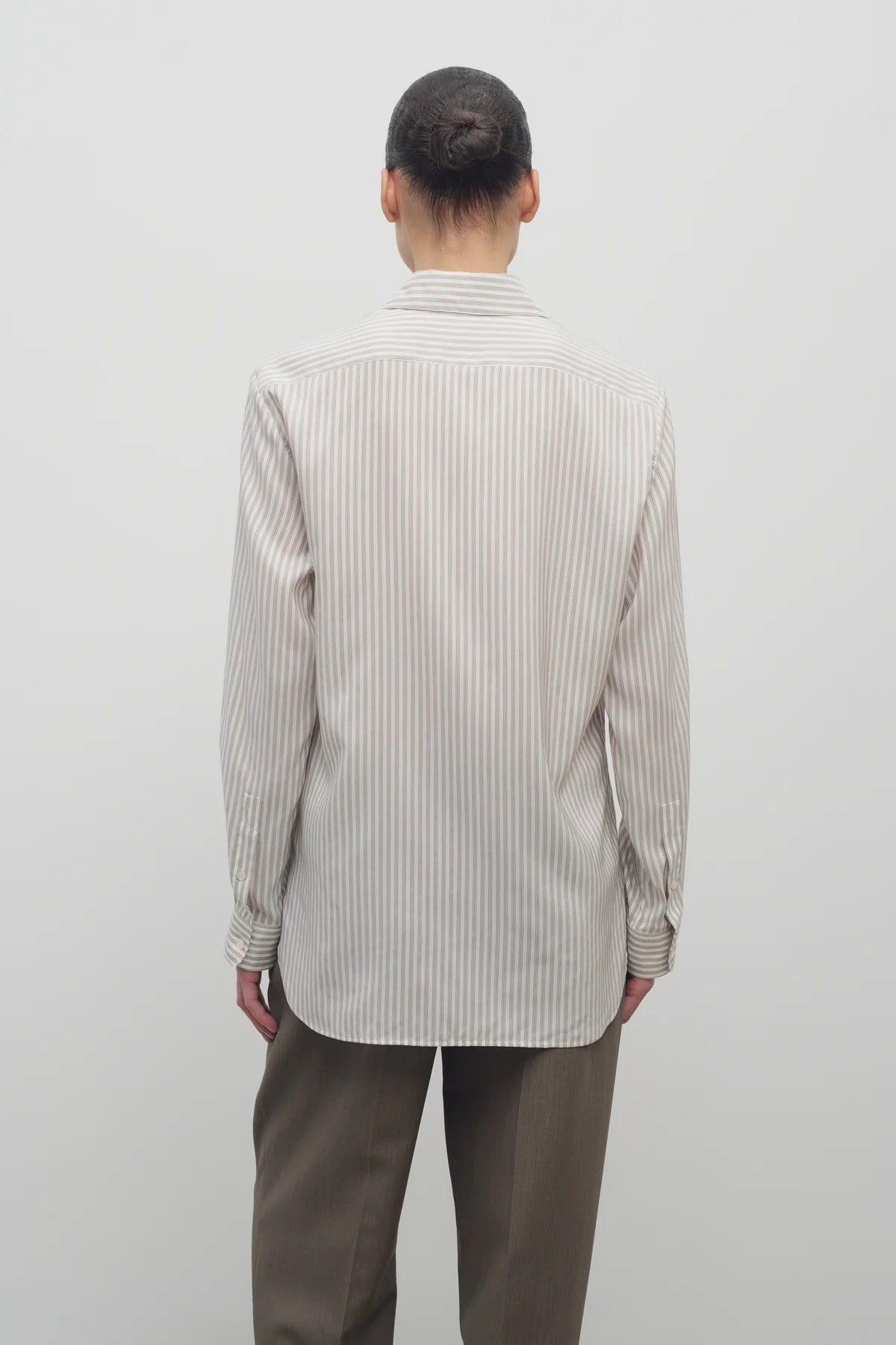 Back view of Long sleeve silk shirt in white with grey on brunette haired model  worn with khaki trousers.