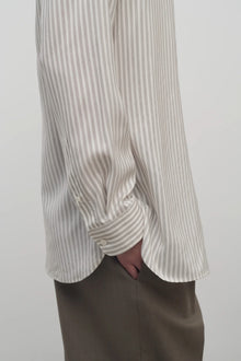 Side closeup view of Long sleeve silk shirt in white with grey on brunette haired model  worn with khaki trousers.
