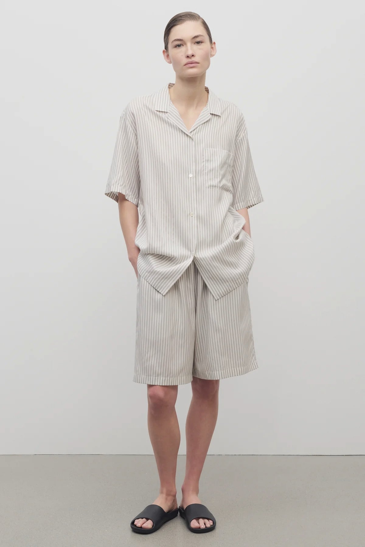 Front view of short with white background, on light brown haired model, worn with matching silk shirt and black sandals.
