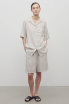 Front view of short with white background, on light brown haired model, worn with matching silk shirt and black sandals.