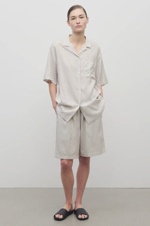 Front view of short with white background, on light brown haired model, worn with matching silk shirt and black sandals.
