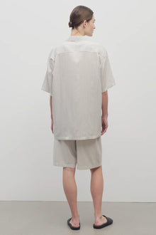Back view of short with white background, on light brown haired model, worn with matching silk shirt and black sandals.