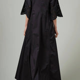 Back view of black rachel long dress on model wearing black flats, against a white background.