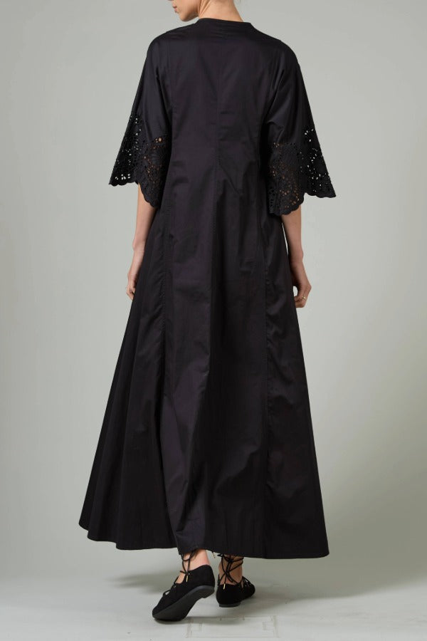 Back view of black rachel long dress on model wearing black flats, against a white background.