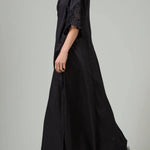 Alternate side view of black rachel long dress on model wearing black flats, against a white background.