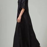 Alternate side view of black rachel long dress on model wearing black flats, against a white background.