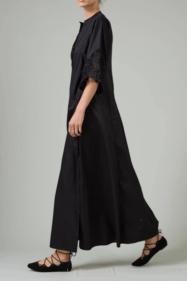 Alternate side view of black rachel long dress on model wearing black flats, against a white background.