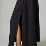 Alternate side closeup view of black rachel long dress on model wearing black flats, against a white background.
