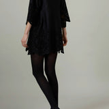 Back view of black rachel mini dress on model wearing black flats, against a white background.