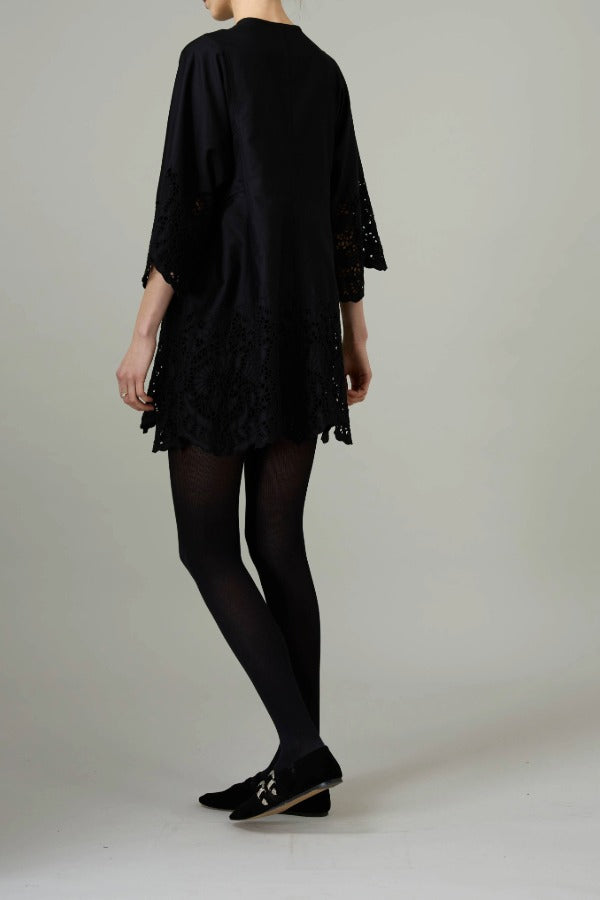 Back view of black rachel mini dress on model wearing black flats, against a white background.