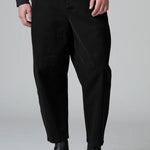 Front view of black japanese tobi trousers on model wearing black top and boots, against a grey background.
