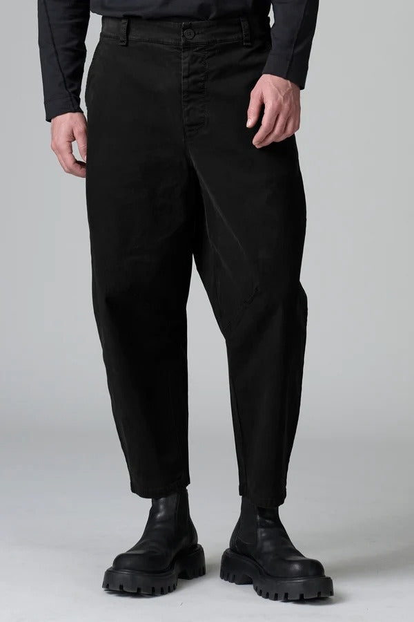 Front view of black japanese tobi trousers on model wearing black top and boots, against a grey background.