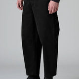Side view of black japanese tobi trousers on model wearing black top and boots, against a grey background.