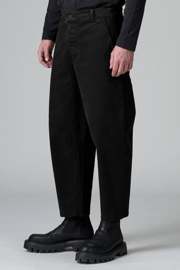Side view of black japanese tobi trousers on model wearing black top and boots, against a grey background.