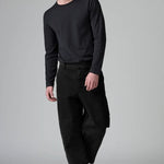 Front view of black japanese tobi trousers on model wearing black top and boots, against a grey background.