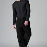 Front view of black japanese tobi trousers on model wearing black top and boots, against a grey background.