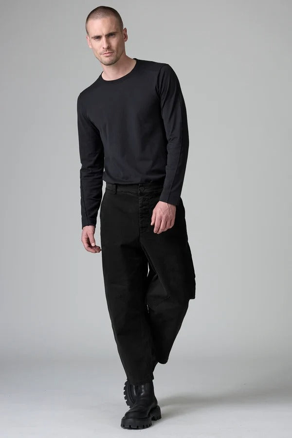 Front view of black japanese tobi trousers on model wearing black top and boots, against a grey background.