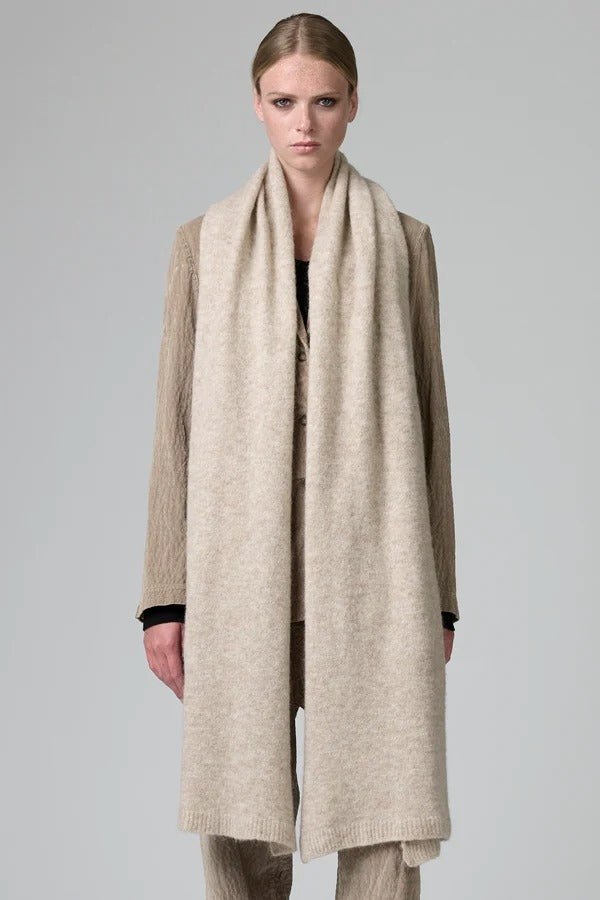 Front view of camel knitted scarf on model wearing matching camel suit, against a grey background.