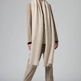 Alternate front view of camel knitted scarf on model wearing matching suit, against a grey background.