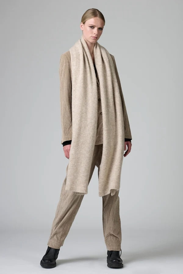 Alternate front view of camel knitted scarf on model wearing matching suit, against a grey background.