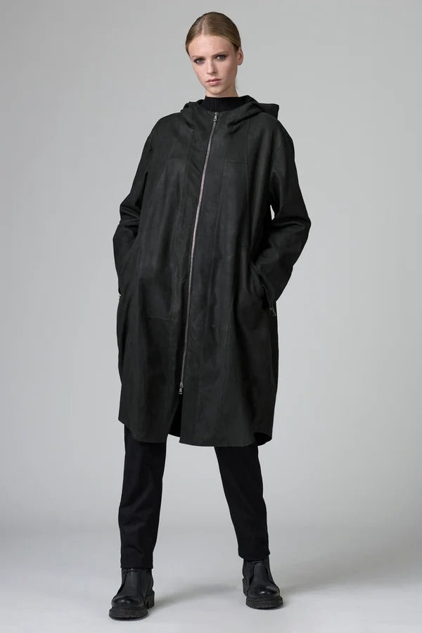 Font view of black long hooded coat on model wearing black pants and boots, against a grey background.
