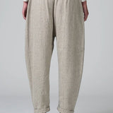 Back view of chalk low crotch comfort fit trouser on model wearing white t-shirt, against a grey background.