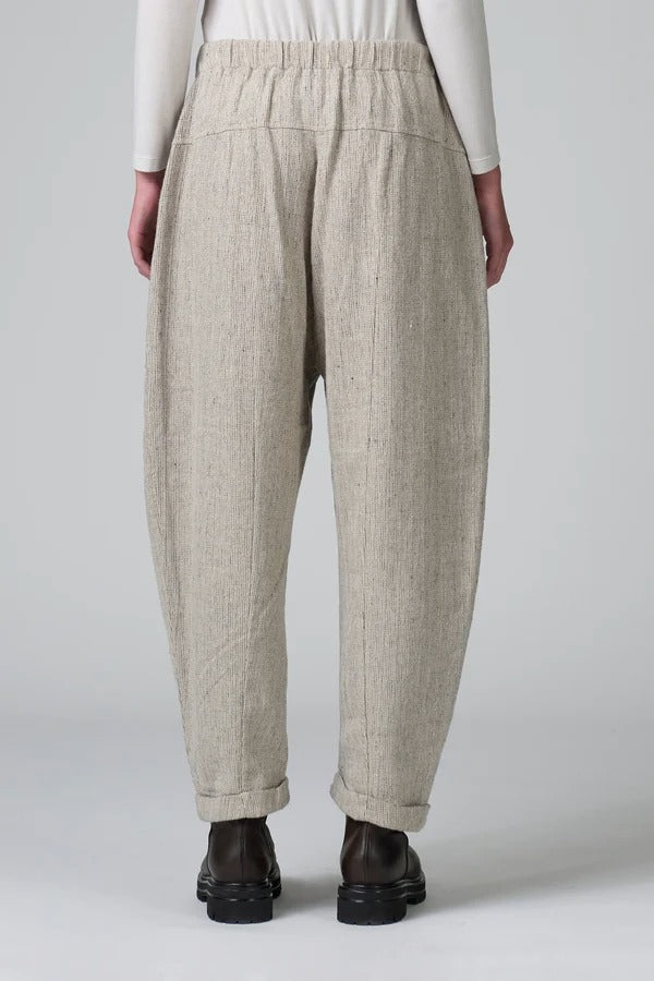 Back view of chalk low crotch comfort fit trouser on model wearing white t-shirt, against a grey background.