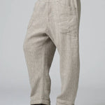 Side view of chalk low crotch comfort fit trouser on model wearing white t-shirt, against a grey background.
