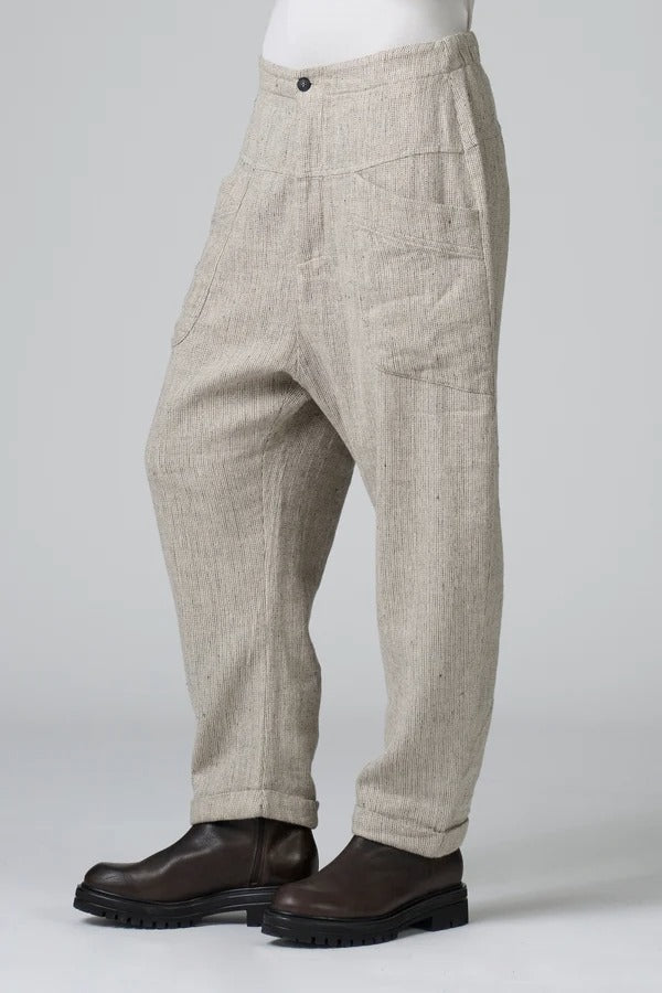 Side view of chalk low crotch comfort fit trouser on model wearing white t-shirt, against a grey background.