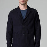 Front view of blue wool regular jacket on model wearing blue shirt and pants, against a grey background.