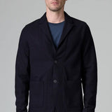 Front view of blue wool regular jacket on model wearing blue shirt and pants, against a grey background.