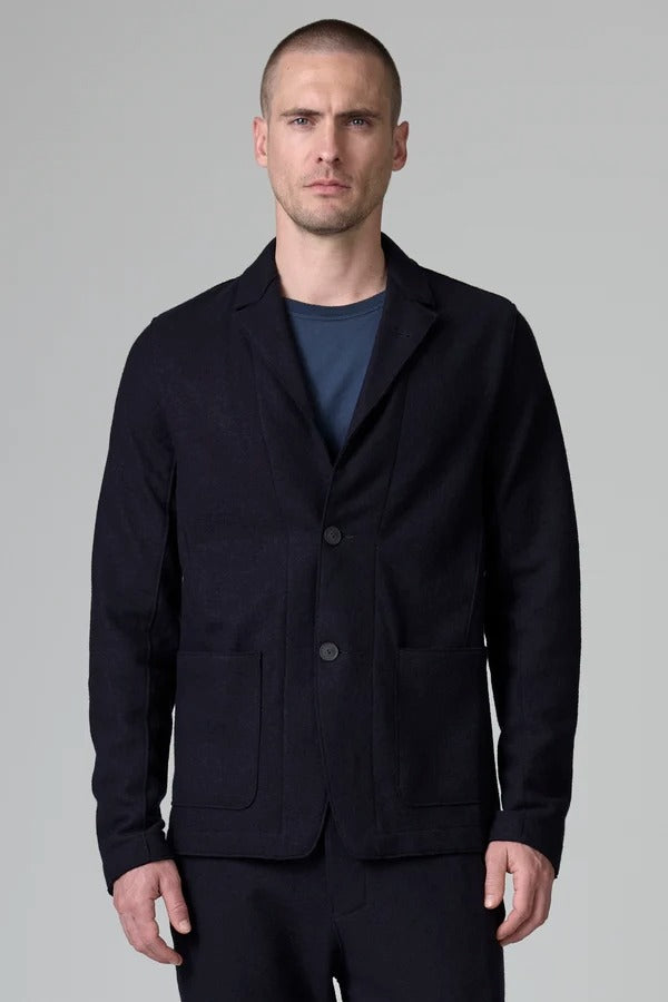 Front view of blue wool regular jacket on model wearing blue shirt and pants, against a grey background.