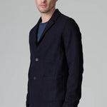 Side view of blue wool regular jacket on model wearing blue shirt and pants, against a grey background.