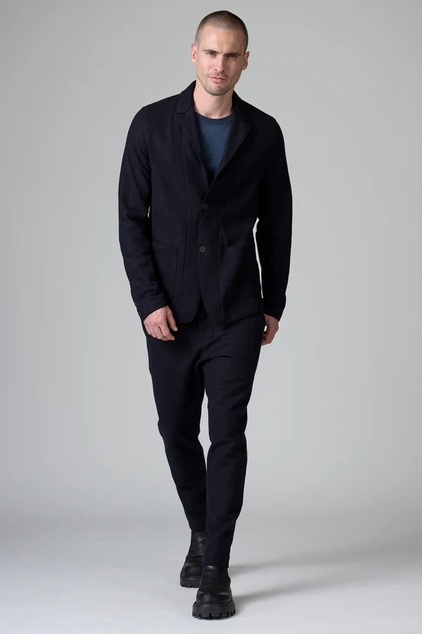 Front view of blue wool regular jacket on model wearing blue shirt and pants with boots, against a grey background.