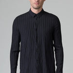 Front view of blue loose fit striped shirt on model wearing black pants, against a grey background.