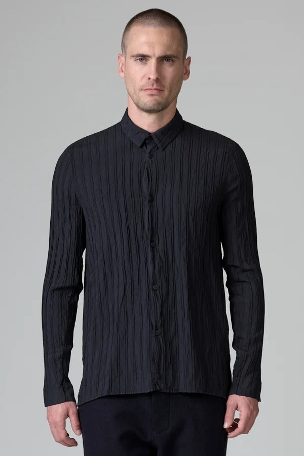 Front view of blue loose fit striped shirt on model wearing black pants, against a grey background.