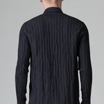 Back view of blue loose fit striped shirt on model wearing black pants, against a grey background.