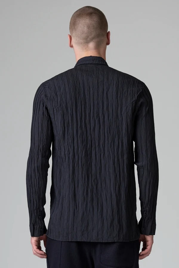 Back view of blue loose fit striped shirt on model wearing black pants, against a grey background.