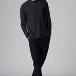 Front view of blue loose fit striped shirt on model wearing black pants, against a grey background.