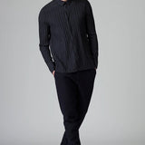 Front view of blue loose fit striped shirt on model wearing black pants, against a grey background.