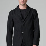 Front view of black regular 2 button jacket on model wearing black top and pants, against a grey background.