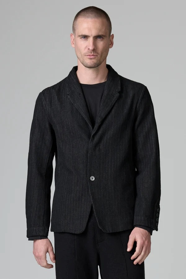 Front view of black regular 2 button jacket on model wearing black top and pants, against a grey background.