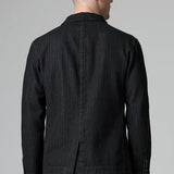 Back view of black regular 2 button jacket on model wearing black pants, against a grey background.
