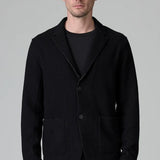 Front view of black/brown regular fit jacket on model wearing black pants, against a grey background.
