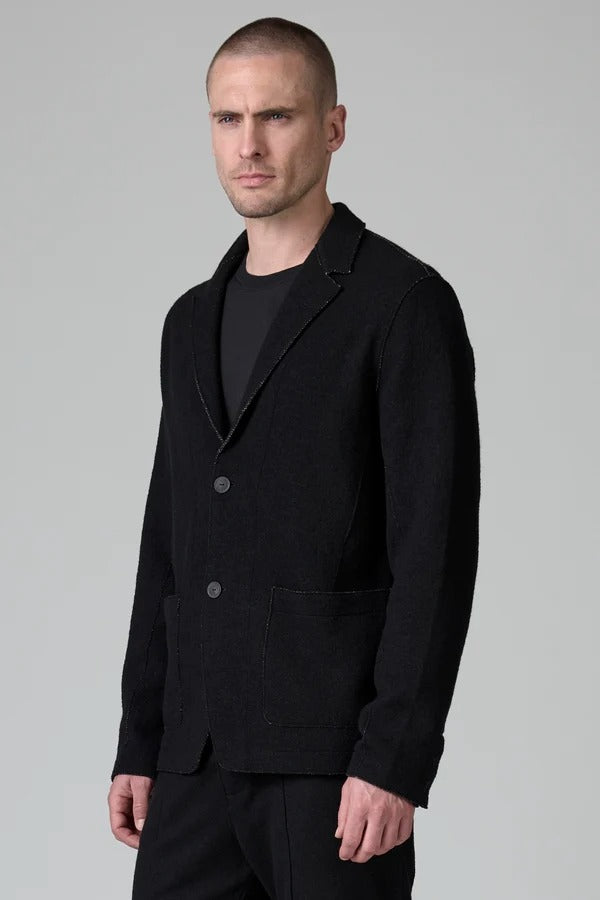 Side view of black/brown regular fit jacket on model wearing black pants, against a grey background.