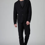 Front view of black/brown regular fit jacket on model wearing black pants, against a grey background.
